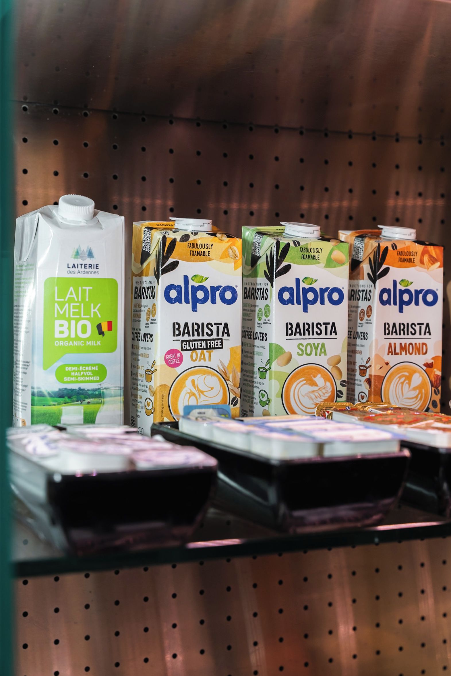 A shelf with various dairy products including organic milk and different flavors of barista coffee milk.
