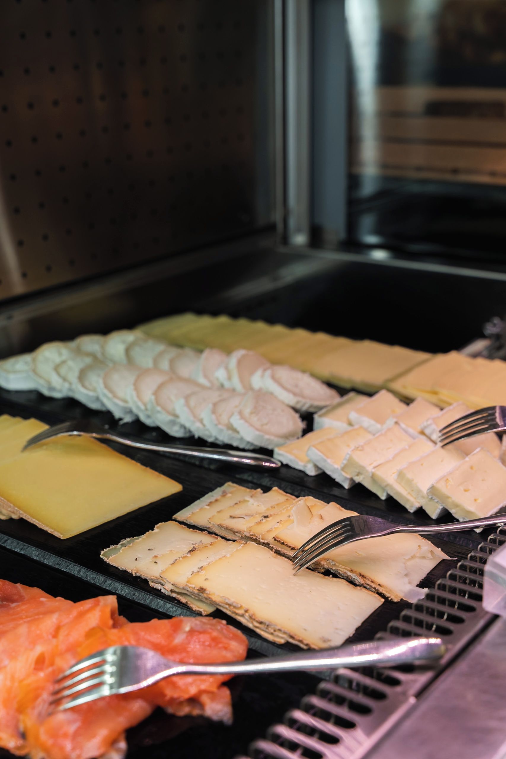 Un buffet proposant une variété de plats, notamment des viandes et des fromages coupés en tranches.