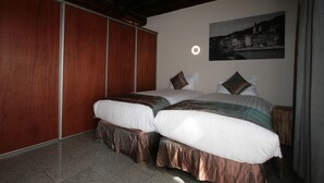Une chambre avec un grand lit, une armoire en bois et un tableau représentant un paysage urbain accroché au mur.
