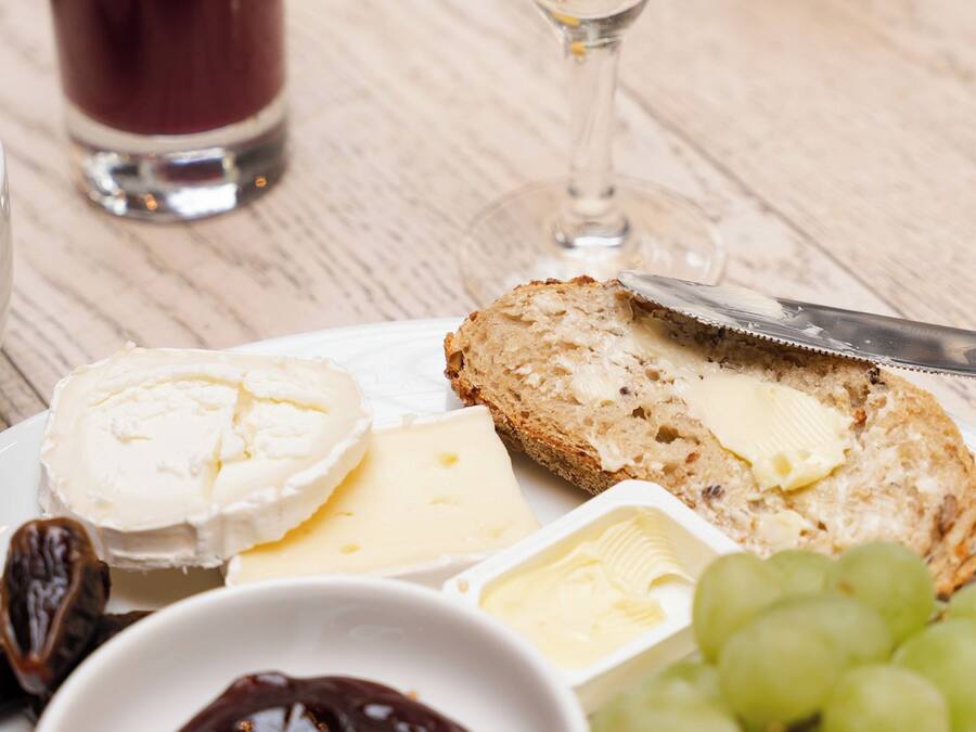 A table with a plate of cheese, crackers, and grapes, accompanied by glasses of juice and a bottle of champagne.