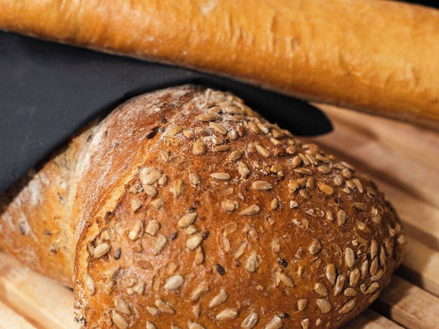 A loaf of bread with seeds on a wooden surface.