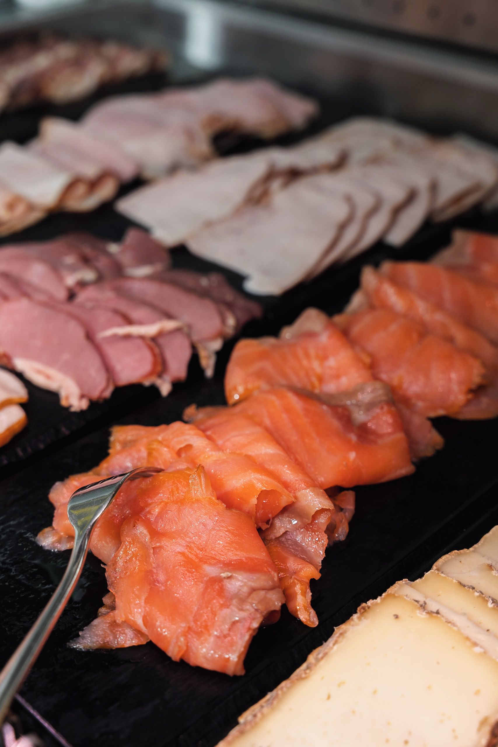 Variedad de carnes a la parrilla, incluyendo jamón y salmón ahumado.