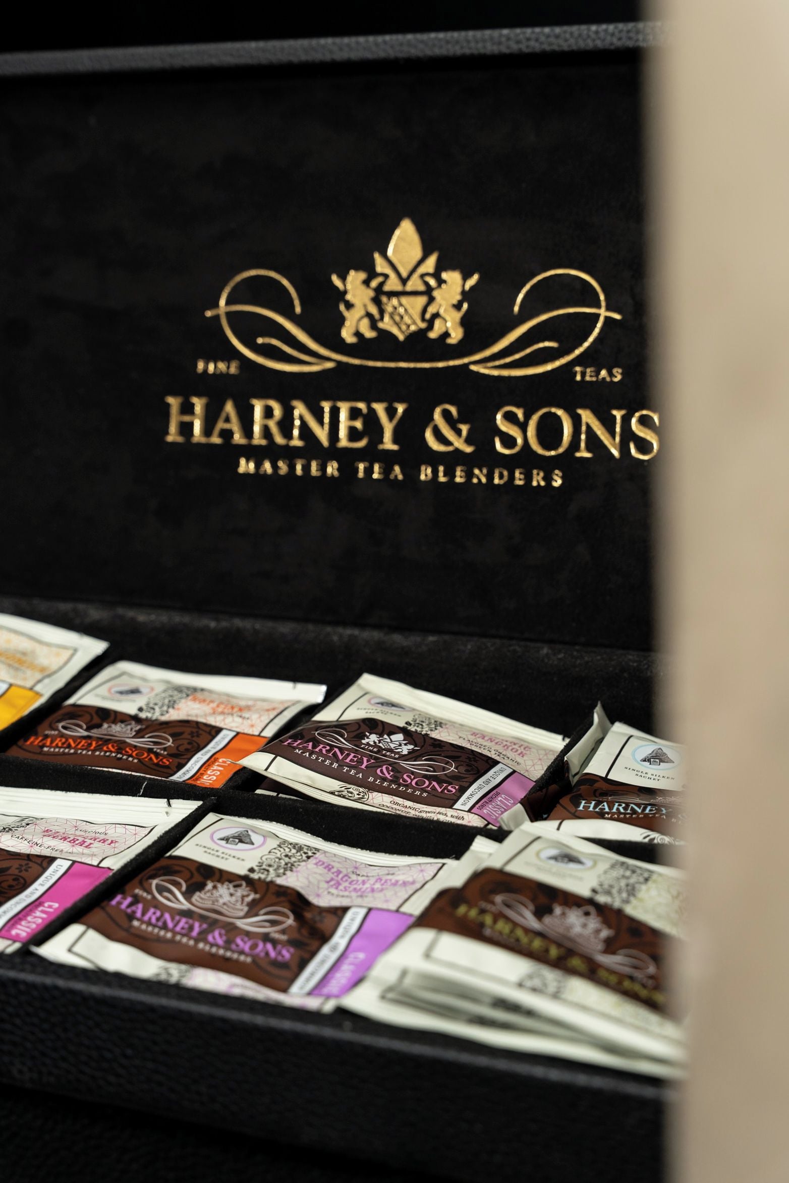 Uma coleção de saquinhos de chá numa caixa preta com a etiqueta 'HARNEY & SONS MASTER TEA BLENDERS'.