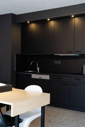 Una cocina moderna con gabinetes negros, un lavamanos de acero inoxidable y un lavavajillas empotrado.