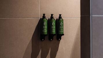 Un dispenser a parete con tre flaconi di shampoo e balsamo Maison eole.