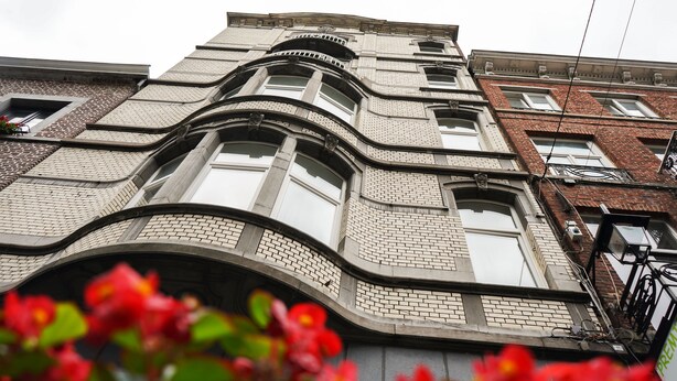 A multi-story building with a curved facade, large windows, and a brick pattern.