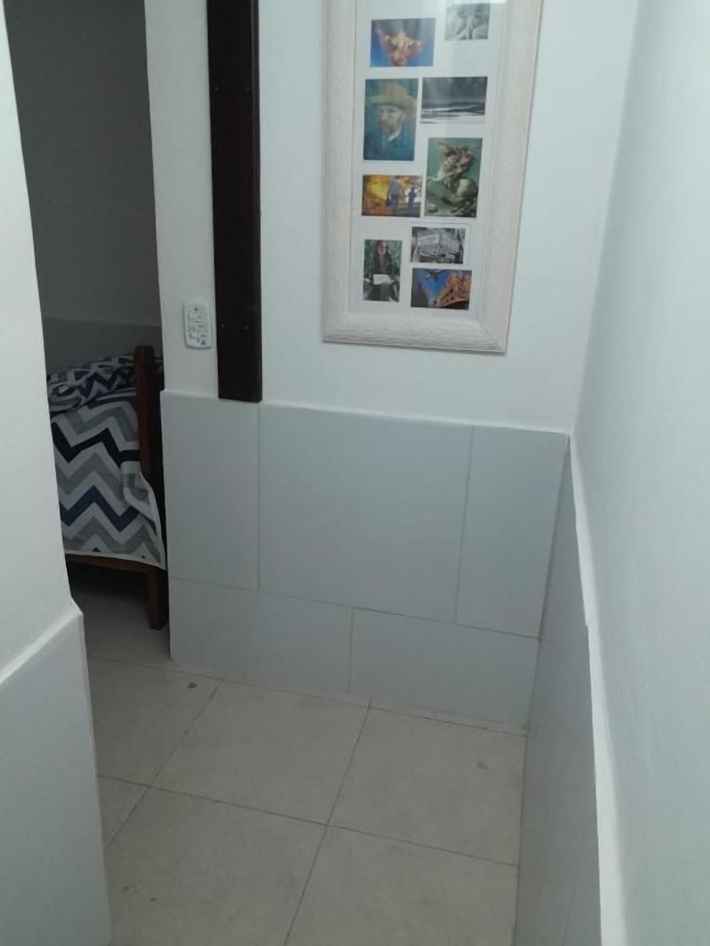 A narrow hallway with a framed collage of photos on the wall, a patterned rug, and a door leading to another room.