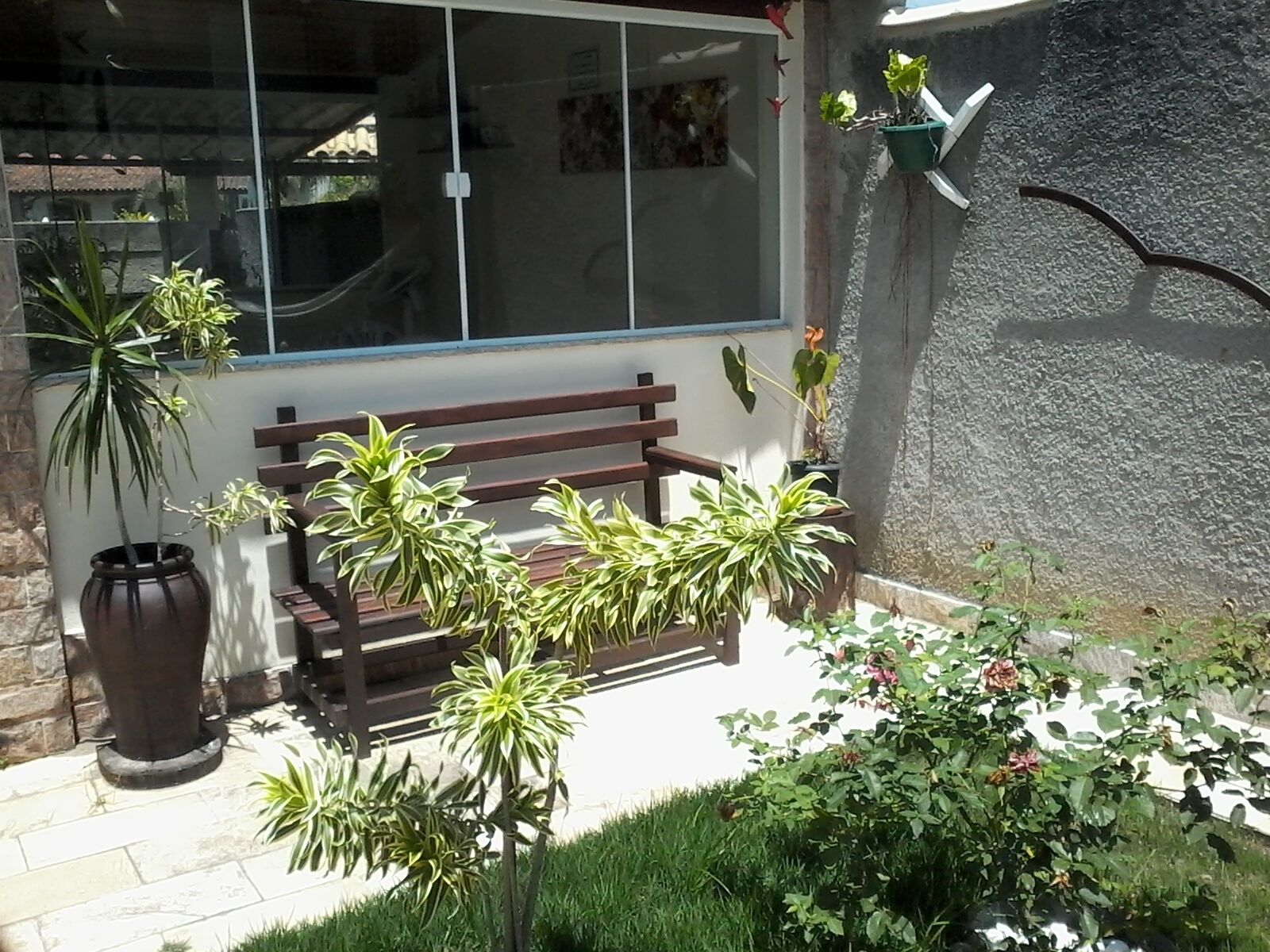 A patio area with a wooden bench, potted plants, and a stone wall.