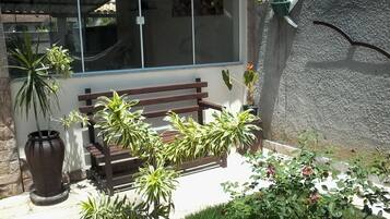 A patio area with a wooden bench, potted plants, and a stone wall.