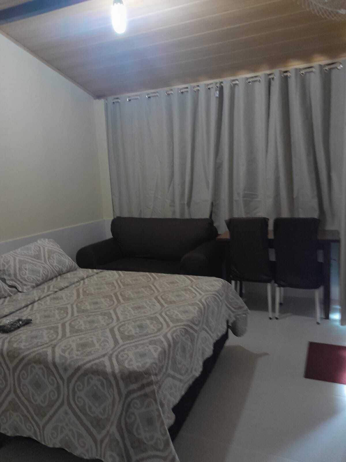 A hotel room with a bed, a sofa, two chairs, and a red rug.