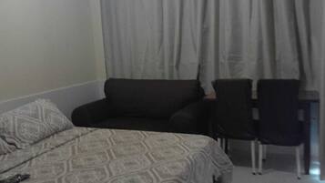 A hotel room with a bed, a sofa, two chairs, and a red rug.