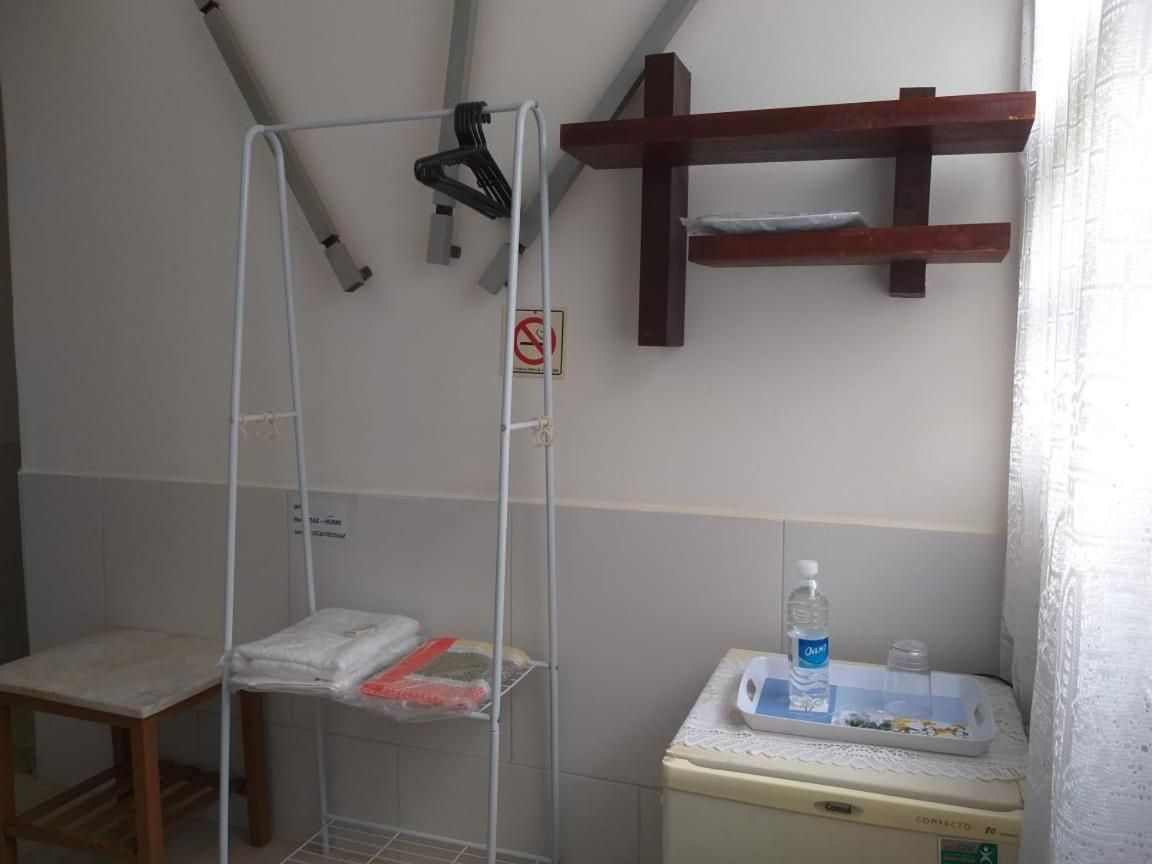 Une salle de bain équipée d’une douche, d’un porte-serviettes, d’une étagère en bois et d’un distributeur d’eau.