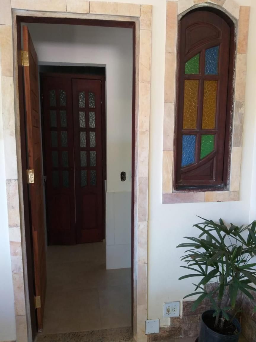 Un pasillo con una puerta de madera y un ventanal con vidrios de colores.