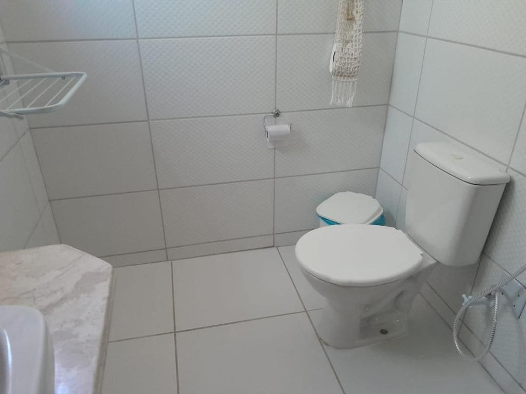 A bathroom with a toilet, a towel rack, and a shower hose.