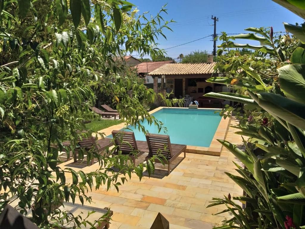 A swimming pool with lounge chairs, surrounded by greenery and a tiled patio area.