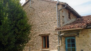 A rustic stone building with a tiled roof, a small window, and a blue door. - Rural Farmhouse with Spacious Garden near Charroux (Charroux)