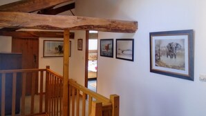 A wooden staircase with a rustic ceiling, a wooden railing, and framed pictures on the wall. - Rural Farmhouse with Spacious Garden near Charroux (Charroux)