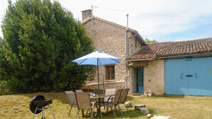 A patio with a table and chairs, a barbecue grill, and a blue umbrella. - Rural Farmhouse with Spacious Garden near Charroux (Charroux)