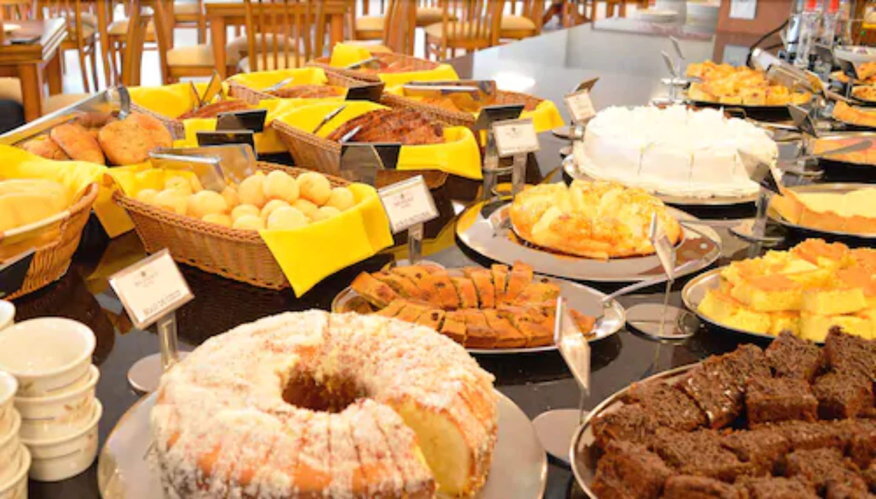 Buffet com diversos pratos, incluindo um bolo grande e várias cestas de comida.