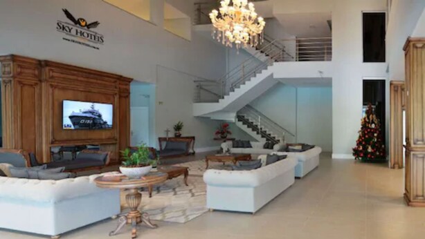 A spacious living area with a large television, a staircase, and a Christmas tree. - Sky Palace Hotel (Gramado)