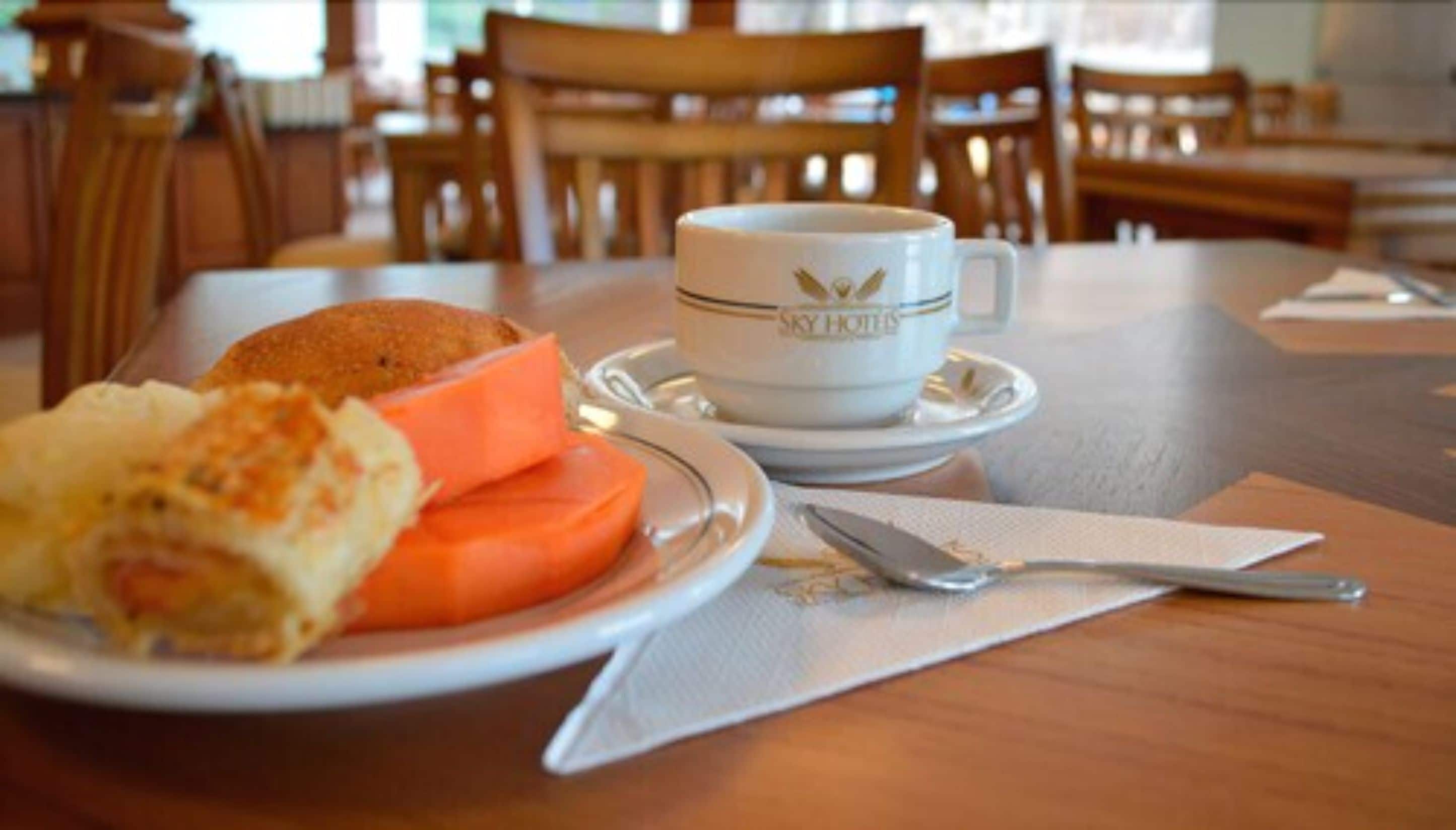 Una mesa de comedor con un plato de comida, una taza de café y cubiertos.