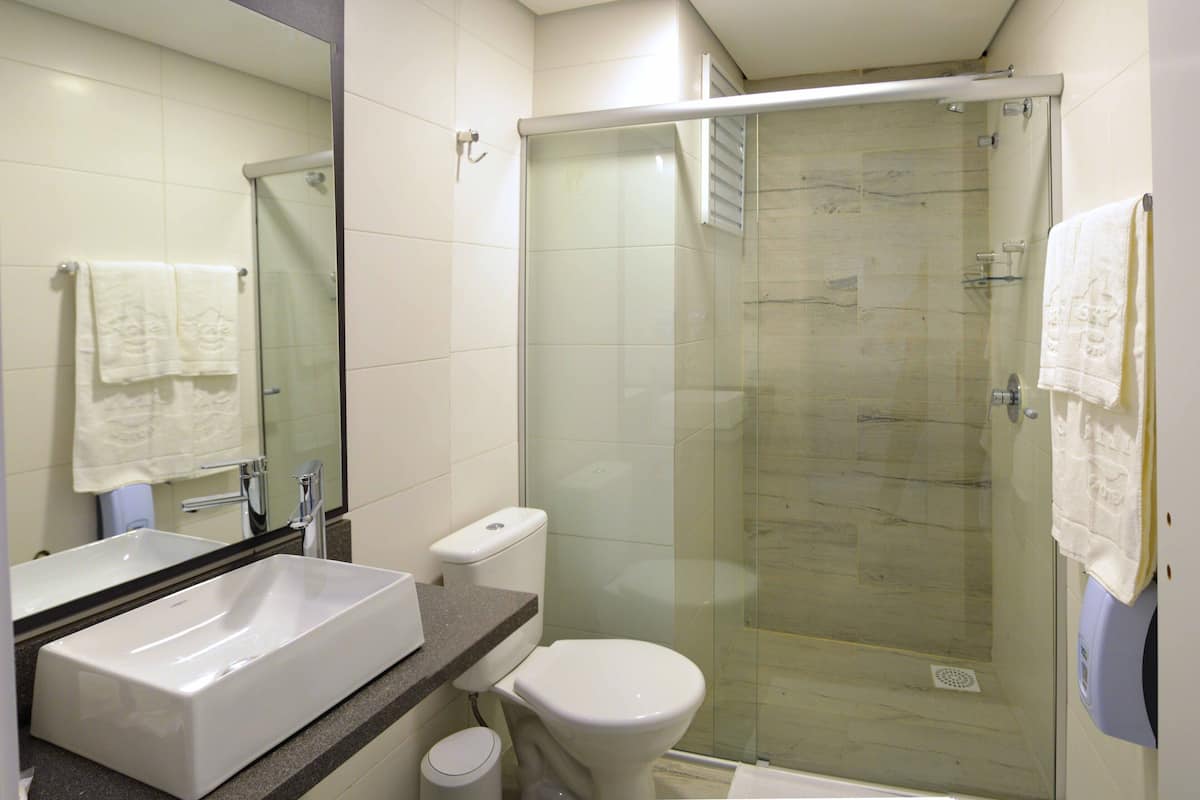 A bathroom with a glass-enclosed shower, a white sink, and a toilet.