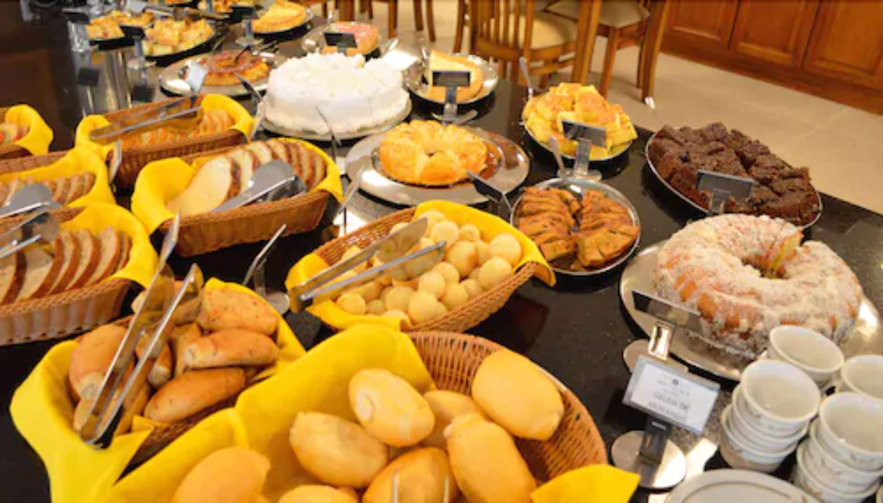 A buffet table with various food items including cakes, pastries, and bread.