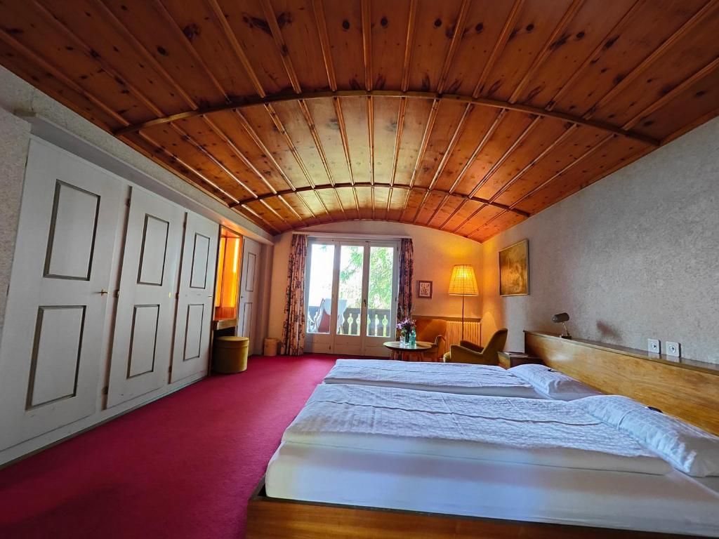 Una camera d'albergo con soffitto in legno, un letto, una scrivania e una sedia.
