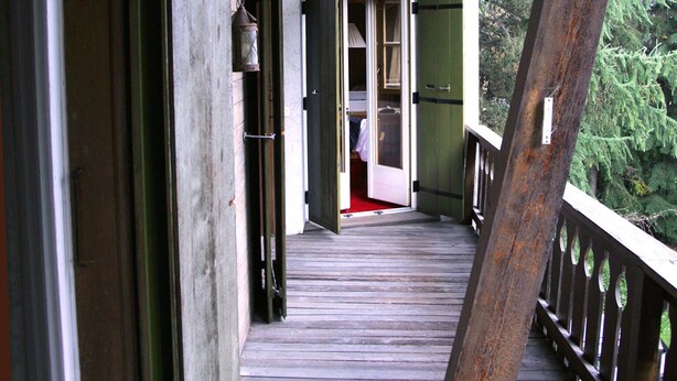 A wooden deck with a railing, leading to a room with a door and a window. - B&B Arche de Noé (Bagnes)