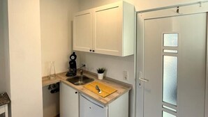 A compact kitchen with white cabinets, a wooden countertop, a sink, and a coffee maker. - Ferienwohnungen AKH Home (Sankt Wendel)