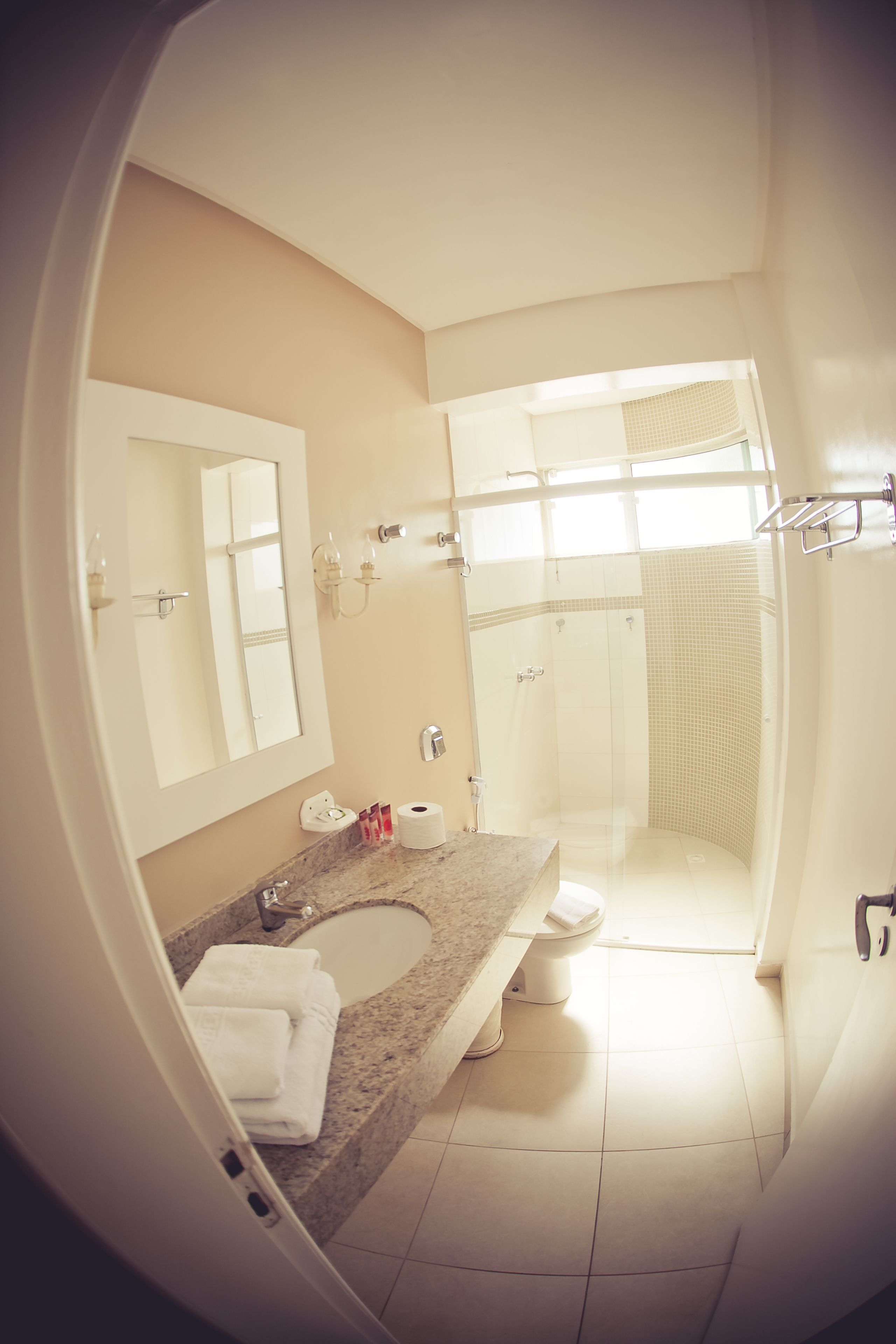 A bathroom with a sink, mirror, toilet, and shower.