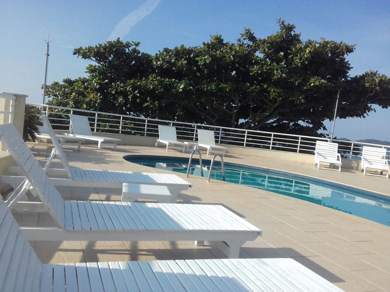 A pool area with white lounge chairs and a swimming pool.
