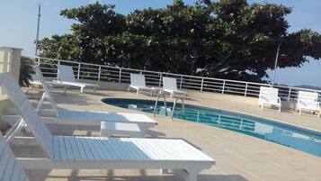 A pool area with white lounge chairs and a swimming pool.