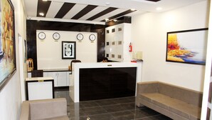 Un hall d’hôtel comprenant un comptoir d’accueil, un espace salon, des horloges et des œuvres d’art accrochées aux murs.