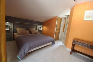 A bedroom with a bed, a bedside table, and a door leading to another room. - Domaine du Clap (Pranles)