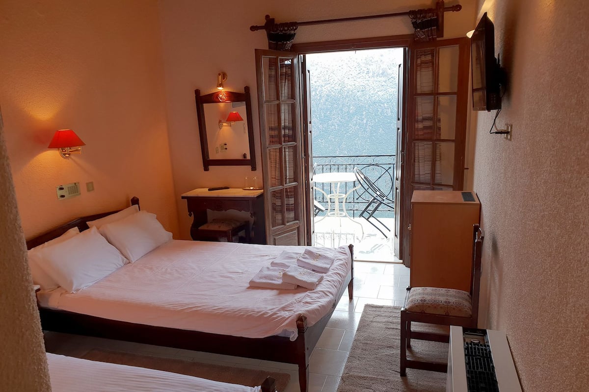 Un dormitorio con dos camas, un escritorio, una silla y un balcón con mesa y sillas.
