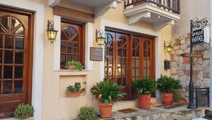 A hotel entrance with large wooden doors, potted plants, and a reception sign. - Hotel Apollo (Delphi)