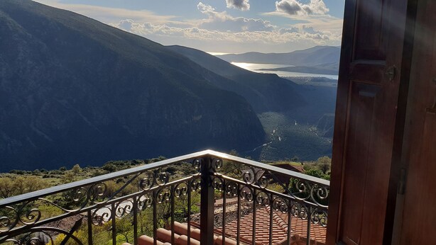 A balcony with a metal railing overlooking a mountainous landscape and a body of water. - Hotel Apollo (Delphi)