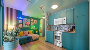 A modern kitchen with teal cabinets, a microwave, and a stove. There is a neon sign on the wall and a plant on the counter. - ‼️Stylish Oceanfront‼️ Stay on Iconic Ocean Drive (Miami Beach)
