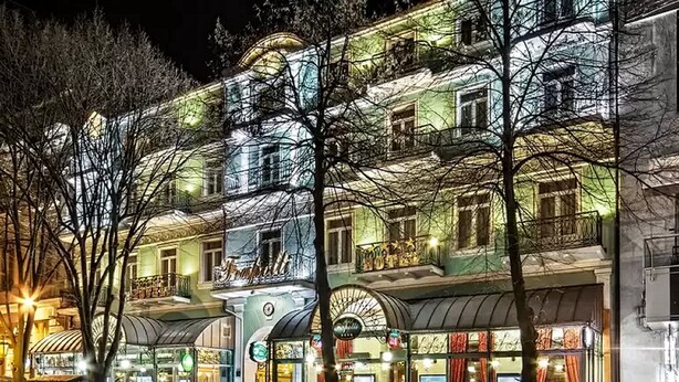 A multi-story hotel with a classic European architectural style, featuring balconies and large windows.