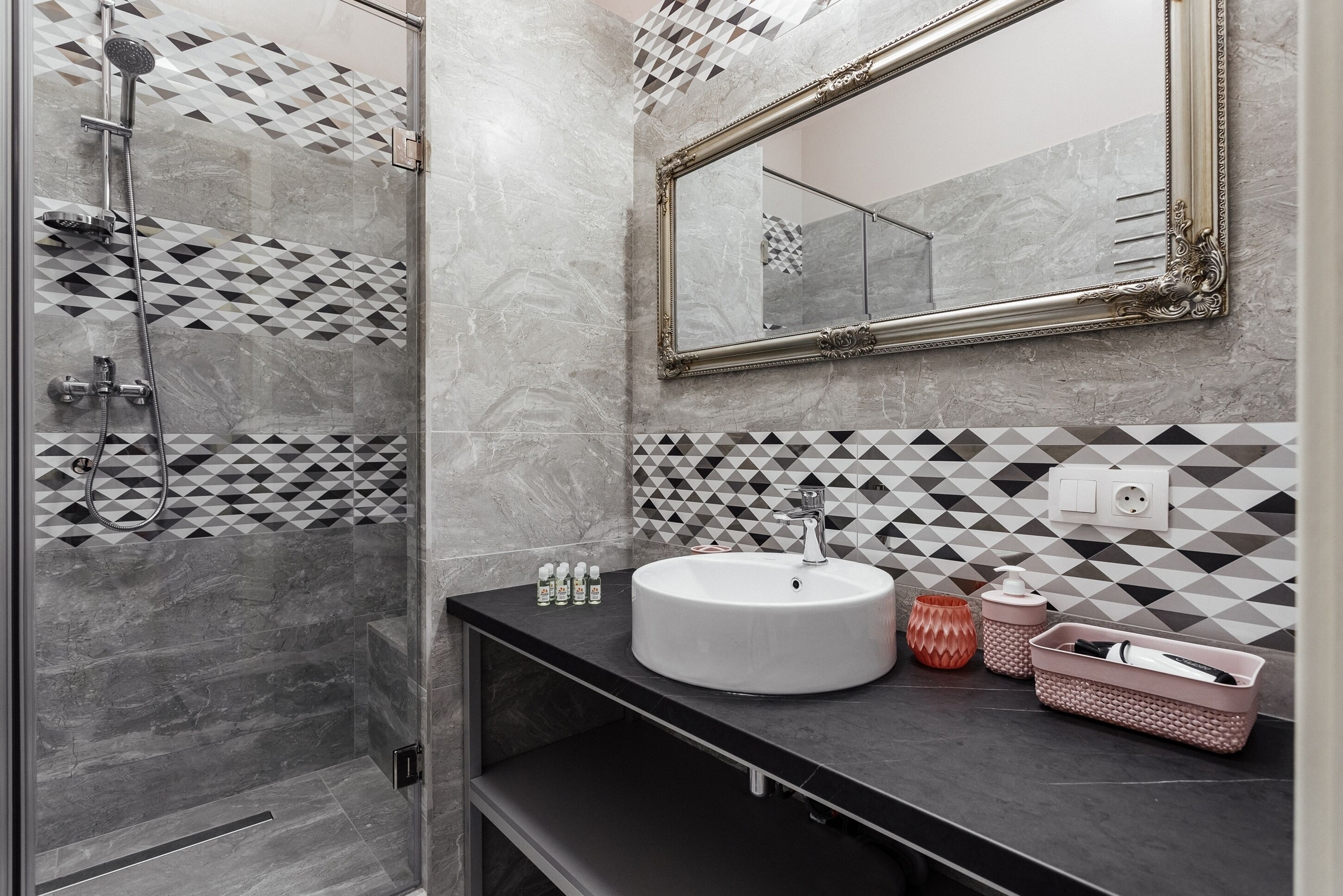 A bathroom with a large mirror, a sink, and a shower.