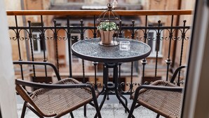 A round table with a potted plant and a glass on a balcony with wicker chairs.