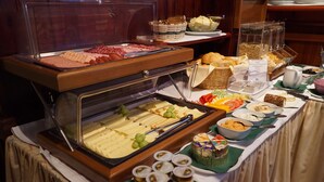 Un bufé con diversos alimentos, incluyendo quesos, carnes y frutas.