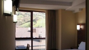 A hotel room with a large window, a bed, a desk, and a chair. - Hotel Ruta de la Plata (Lena)