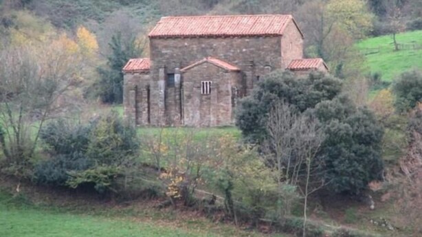A stone building with a red-tiled roof, surrounded by trees and grass. - Hotel Ruta de la Plata (Lena)