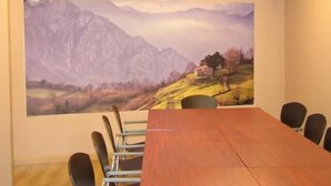 A conference room with a large painting of a mountainous landscape on the wall, a long wooden table, and six chairs. - Hotel Ruta de la Plata (Lena)