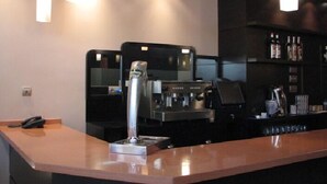 A modern bar area with a coffee machine, a phone on the counter, and a shelf with bottles. - Hotel Ruta de la Plata (Lena)