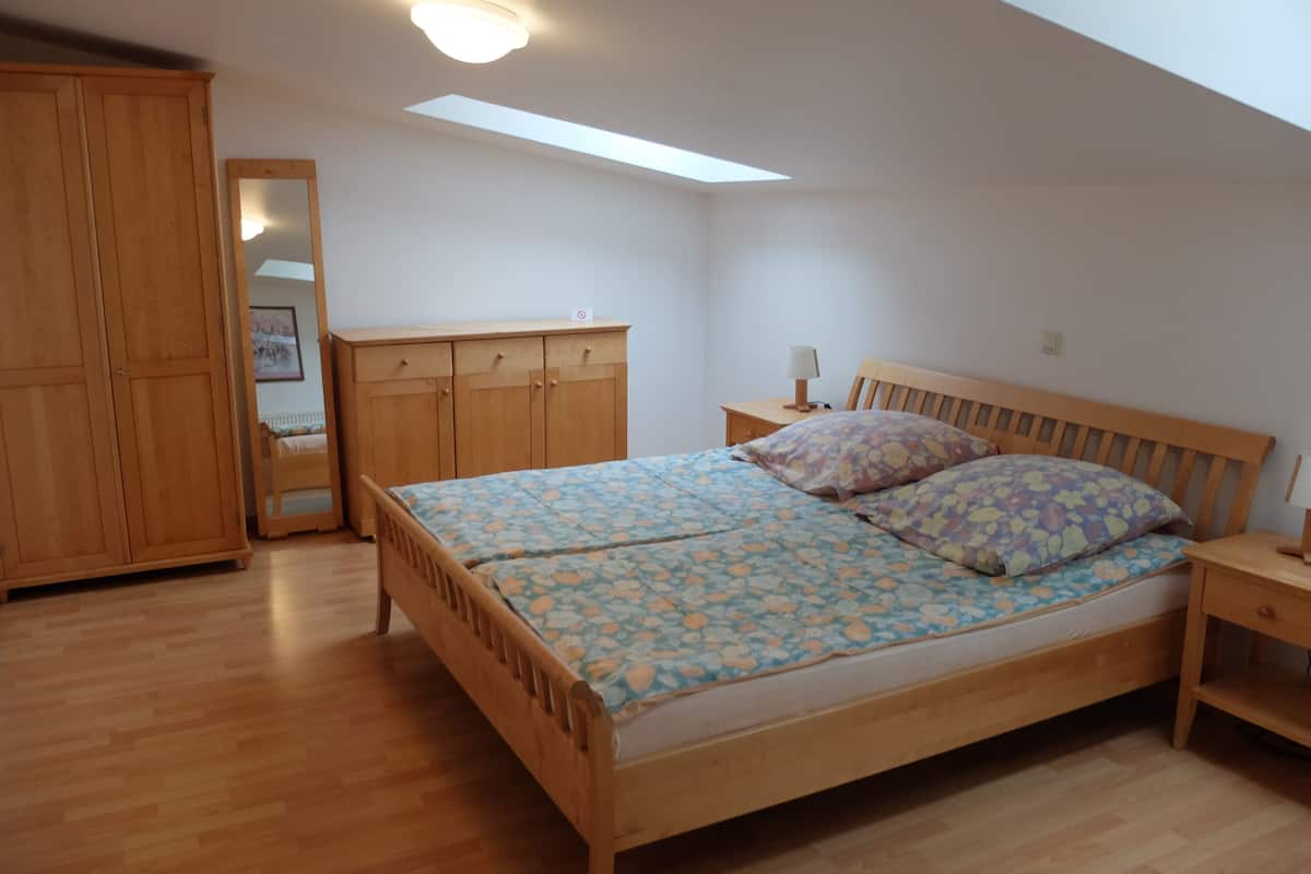 Ein Schlafzimmer mit einem hölzernen Bett, einem Nachttisch, einem Kleiderschrank und einem Oberlicht.
