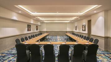 A conference room with a long table, black chairs, and a patterned carpet.