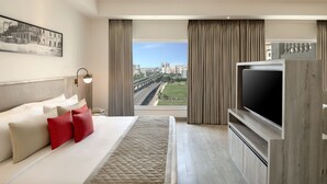 A modern hotel room with a large bed, a flat-screen TV, a city view, and a framed picture on the wall. - Lemon Tree Premier New Town Kolkata (Barasat)